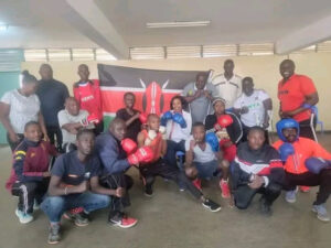 A group of men and women posing for a photo inside a boxing gym