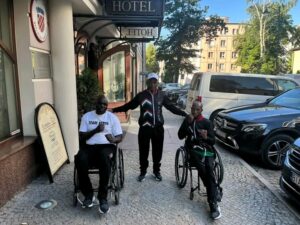 Aman standing in between two other men on wheelchairs